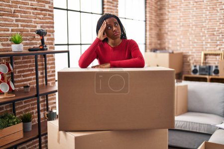 Foto de Mujer afroamericana embalaje caja de cartón en nuevo hogar - Imagen libre de derechos