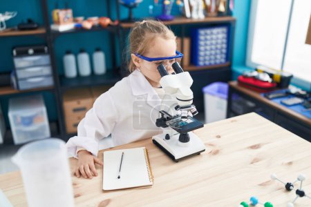 Photo for Adorable blonde girl student using microscope at laboratory classroom - Royalty Free Image