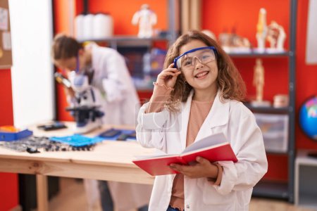 Téléchargez les photos : Two kids students using microscope reading notebook at laboratory classroom - en image libre de droit