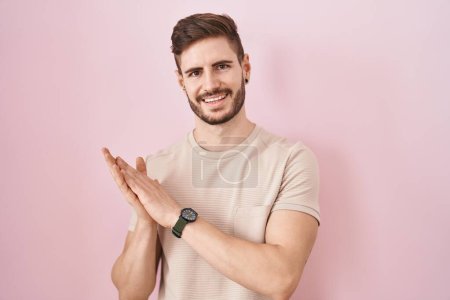 Foto de Hispanic man with beard standing over pink background clapping and applauding happy and joyful, smiling proud hands together - Imagen libre de derechos
