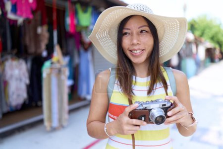 Téléchargez les photos : Jeune femme asiatique touristique en utilisant une caméra vintage au marché de la rue - en image libre de droit