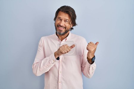 Photo for Handsome middle age man wearing elegant shirt background pointing to the back behind with hand and thumbs up, smiling confident - Royalty Free Image