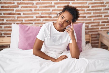 Foto de Mujer afroamericana estresada sentada en la cama en el dormitorio - Imagen libre de derechos
