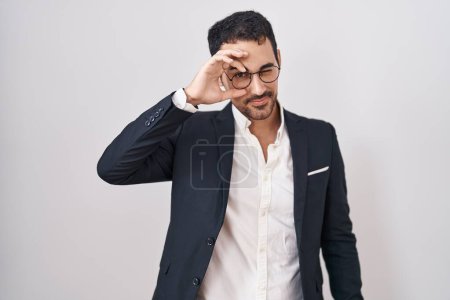 Photo for Handsome business hispanic man standing over white background doing ok gesture with hand smiling, eye looking through fingers with happy face. - Royalty Free Image