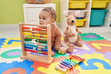 Photo for Adorable hispanic toddler playing with abacus sitting on floor at kindergarten - Royalty Free Image