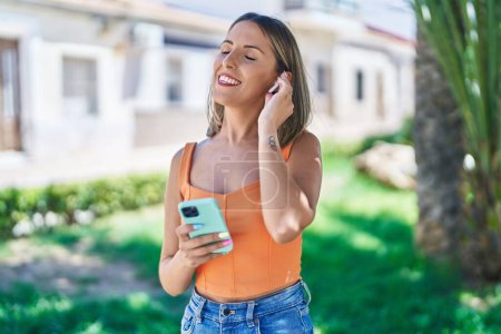 Téléchargez les photos : Jeune belle femme hispanique souriant confiant écouter de la musique au parc - en image libre de droit