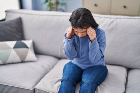 Photo for Young woman with down syndrome stressed sitting on sofa at home - Royalty Free Image