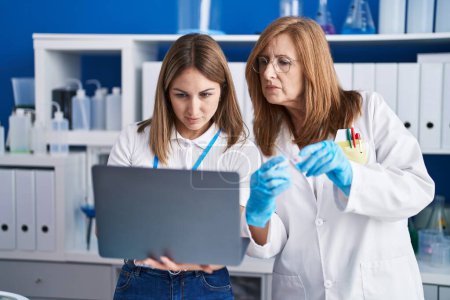 Téléchargez les photos : Mère et fille scientifiques utilisant un ordinateur portable travaillant au laboratoire - en image libre de droit