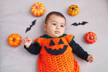 Téléchargez les photos : Adorable bébé hispanique portant Halloween coutume couché sur le canapé à la maison - en image libre de droit
