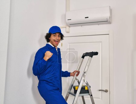 Foto de Hispanic man with curly hair working at home renovation screaming proud, celebrating victory and success very excited with raised arms - Imagen libre de derechos