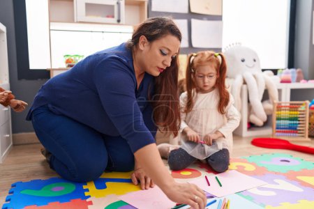 Téléchargez les photos : Teacher and student drawing on paper sitting on floor at kindergarten - en image libre de droit
