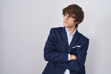 Téléchargez les photos : Entreprise hispanique jeune homme portant des lunettes regardant sur le côté avec les bras croisés convaincu et confiant - en image libre de droit