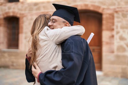 Foto de Man and woman mother and son hugging each other celebrating graduation at university - Imagen libre de derechos