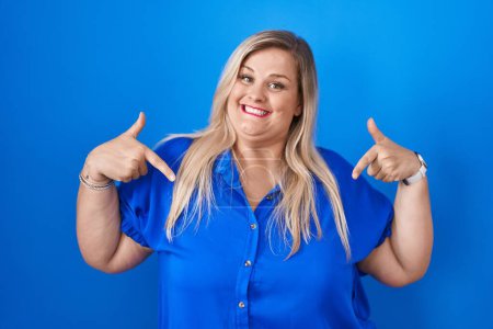Photo for Caucasian plus size woman standing over blue background looking confident with smile on face, pointing oneself with fingers proud and happy. - Royalty Free Image