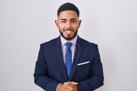 Photo for Young hispanic man wearing business suit and tie with hands together and crossed fingers smiling relaxed and cheerful. success and optimistic - Royalty Free Image