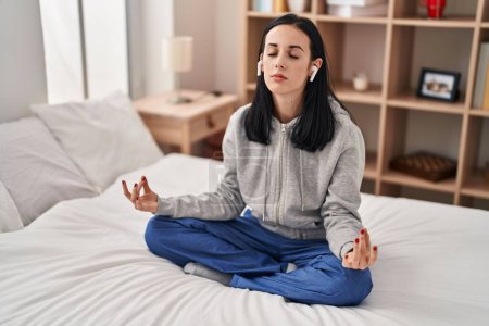 Téléchargez les photos : Young caucasian woman doing yoga exercise sitting on bed at bedroom - en image libre de droit