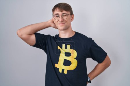 Photo for Caucasian blond man wearing bitcoin t shirt suffering of neck ache injury, touching neck with hand, muscular pain - Royalty Free Image