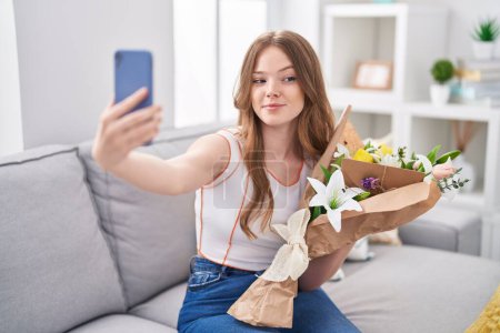 Foto de Mujer caucásica sosteniendo ramo de flores blancas tomando una foto selfie sonriendo mirando a un lado y mirando hacia otro pensando. - Imagen libre de derechos