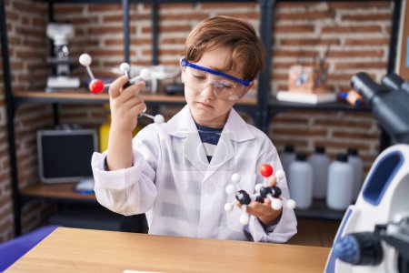 Foto de Adorable niño hispano estudiante sosteniendo moléculas en el aula de laboratorio - Imagen libre de derechos