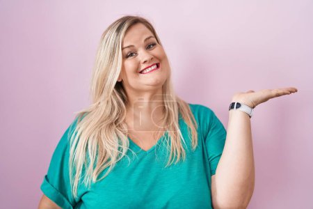 Téléchargez les photos : Caucasian plus size woman standing over pink background smiling cheerful presenting and pointing with palm of hand looking at the camera. - en image libre de droit