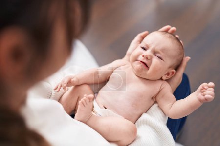Foto de Adorable caucasian baby on mother hands crying at home - Imagen libre de derechos