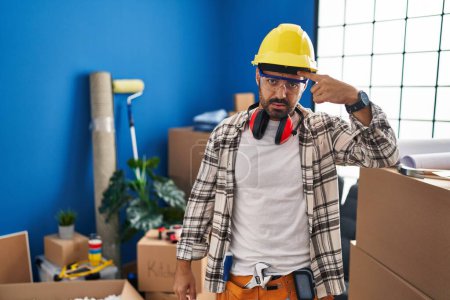 Photo for Young hispanic man with beard working at home renovation pointing unhappy to pimple on forehead, ugly infection of blackhead. acne and skin problem - Royalty Free Image