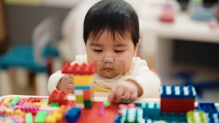 Téléchargez les photos : Adorable hispanic baby playing with construction blocks sitting on table at kindergarten - en image libre de droit