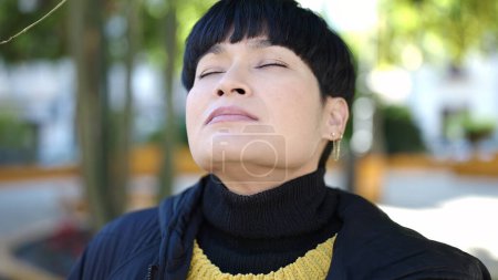 Photo for Young chinese woman breathing with closed eyes at park - Royalty Free Image