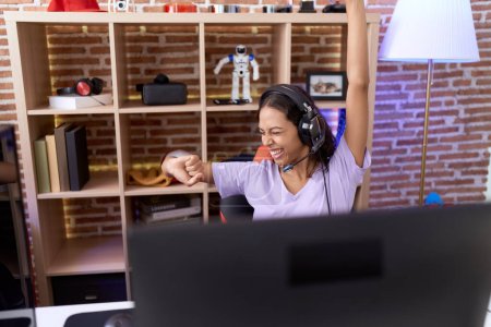 Téléchargez les photos : Young african american woman streamer playing video game with winner expression at gaming room - en image libre de droit