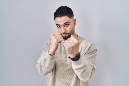 Téléchargez les photos : Young handsome man standing over isolated background ready to fight with fist defense gesture, angry and upset face, afraid of problem - en image libre de droit