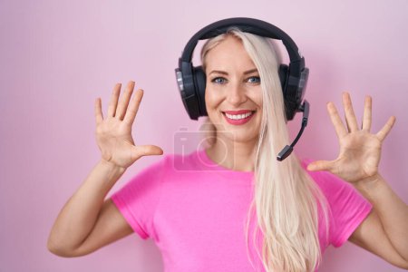 Téléchargez les photos : Caucasian woman listening to music using headphones showing and pointing up with fingers number ten while smiling confident and happy. - en image libre de droit