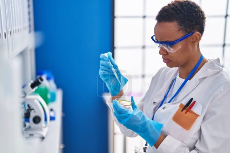 Photo for African american woman scientist pouring liquid on sample at laboratory - Royalty Free Image