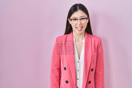 Téléchargez les photos : Chinese business young woman wearing glasses sticking tongue out happy with funny expression. emotion concept. - en image libre de droit