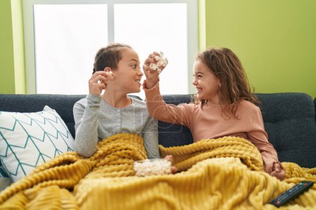 Téléchargez les photos : Two kids eating popcorn watching movie at home - en image libre de droit