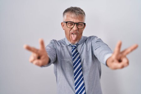 Photo for Hispanic business man with grey hair wearing glasses smiling with tongue out showing fingers of both hands doing victory sign. number two. - Royalty Free Image