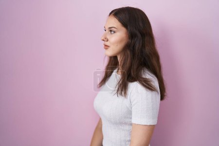 Photo for Young hispanic girl standing over pink background looking to side, relax profile pose with natural face and confident smile. - Royalty Free Image