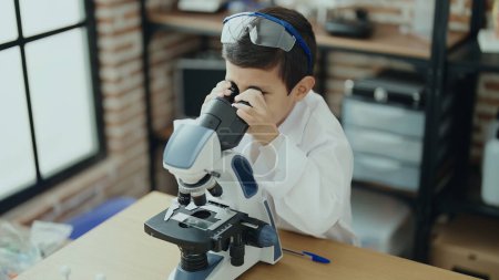 Téléchargez les photos : Adorable élève hispanique garçon en utilisant le microscope à la salle de classe de laboratoire - en image libre de droit
