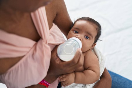 Téléchargez les photos : Africain américain bébé sucer biberon d'alimentation à chambre - en image libre de droit