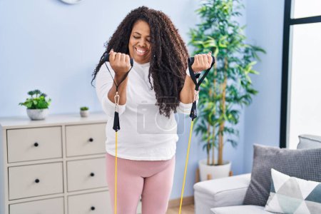 Téléchargez les photos : African american woman smiling confident using elastic band training at home - en image libre de droit