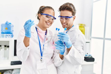 Foto de Hombre y mujer vistiendo uniforme científico sosteniendo tubo de ensayo en laboratorio - Imagen libre de derechos