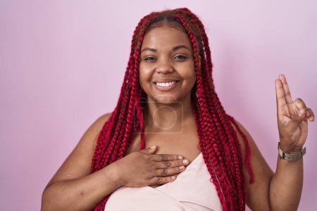 Téléchargez les photos : African american woman with braided hair standing over pink background smiling swearing with hand on chest and fingers up, making a loyalty promise oath - en image libre de droit