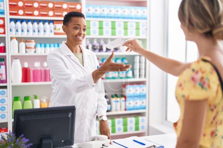 Foto de Farmacéutica afroamericana que tiene prescripción al cliente en farmacia - Imagen libre de derechos