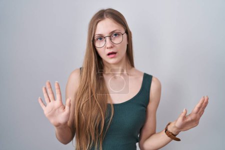 Téléchargez les photos : Young caucasian woman standing over white background moving away hands palms showing refusal and denial with afraid and disgusting expression. stop and forbidden. - en image libre de droit