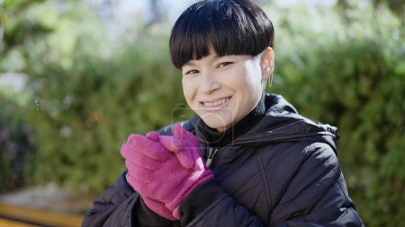 Téléchargez les photos : Jeune femme chinoise souriante et confiante portant des gants d'hiver au parc - en image libre de droit