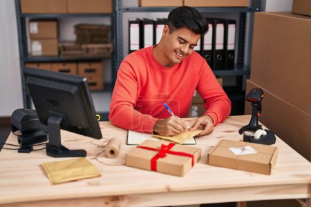 Photo for Young hispanic man ecommerce business worker writing on package at office - Royalty Free Image