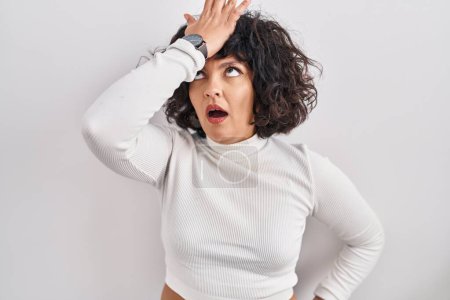 Photo for Hispanic woman with curly hair standing over isolated background surprised with hand on head for mistake, remember error. forgot, bad memory concept. - Royalty Free Image