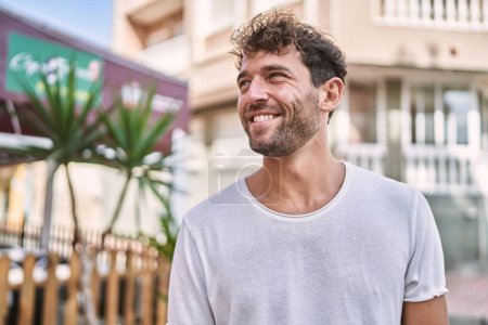 Foto de Joven hombre hispano sonriendo confiado caminando por la calle - Imagen libre de derechos