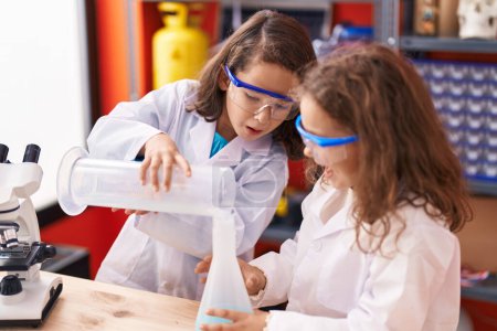 Téléchargez les photos : Two kids students pouring liquid on test tube at laboratory classroom - en image libre de droit