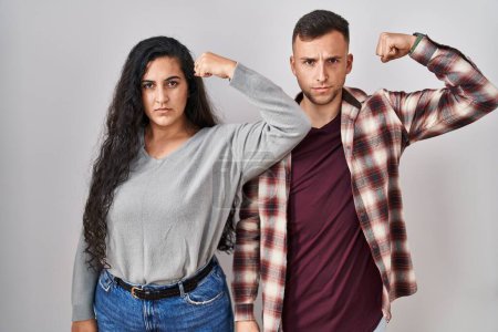 Photo for Young hispanic couple standing over white background strong person showing arm muscle, confident and proud of power - Royalty Free Image