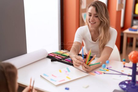 Téléchargez les photos : Enseignant et tout-petit ayant une leçon de planètes tenant des crayons de couleur en classe - en image libre de droit